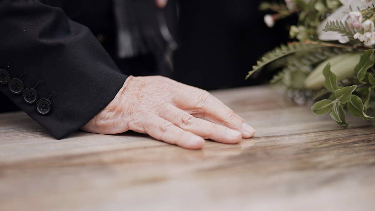 A hand resting on top of a casket