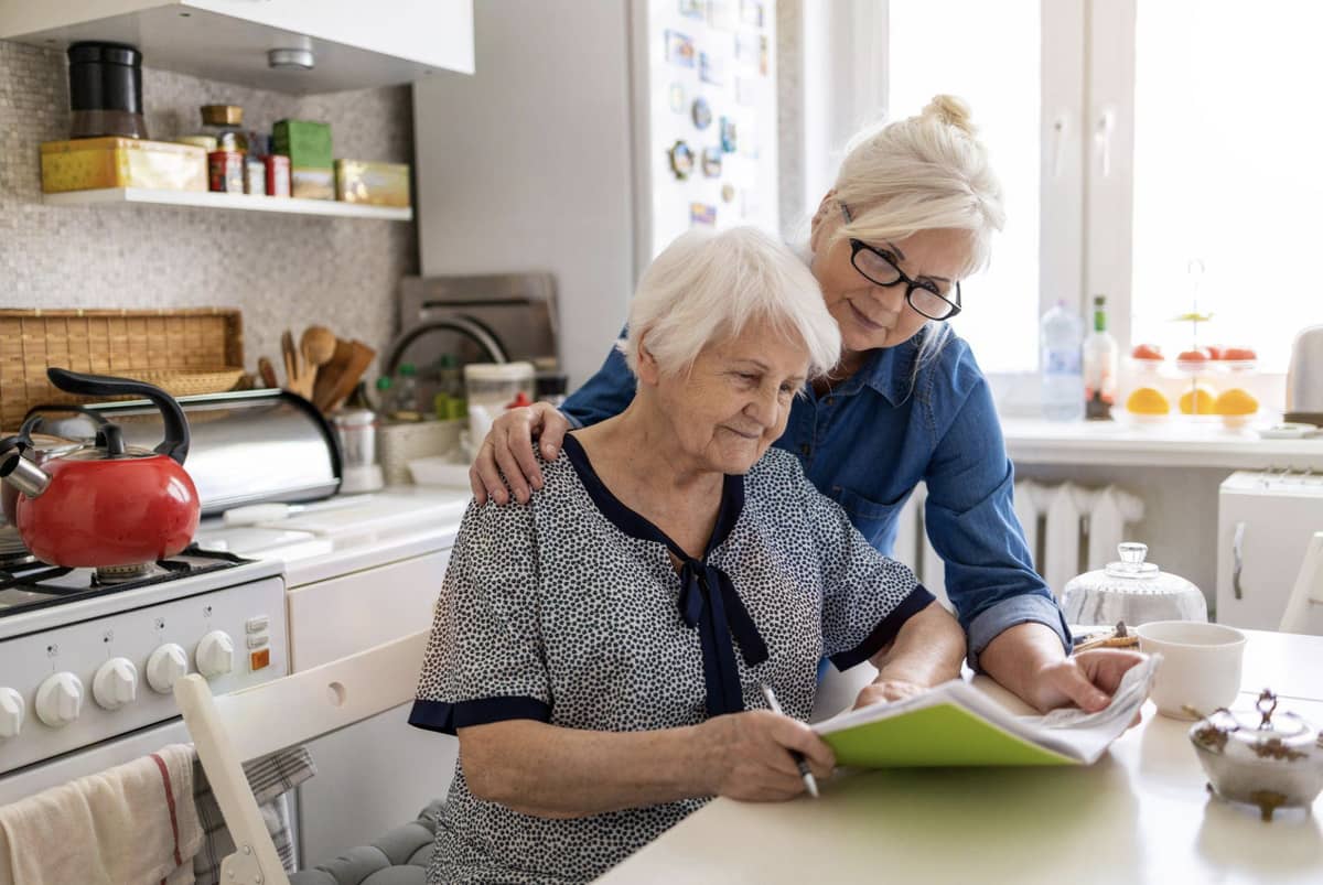 A senior woman with a younger woman (her daughter) going over documents