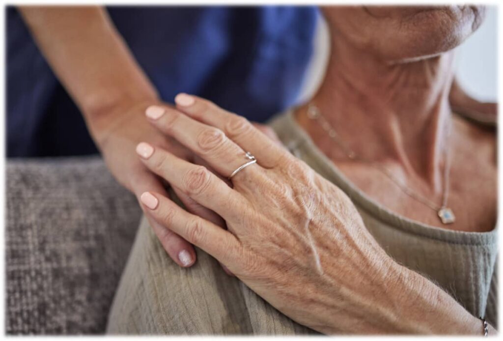 Someone with the hands lovingly on a senior woman's shoulder