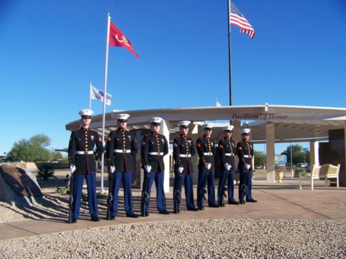 Men in uniform standing in front flags