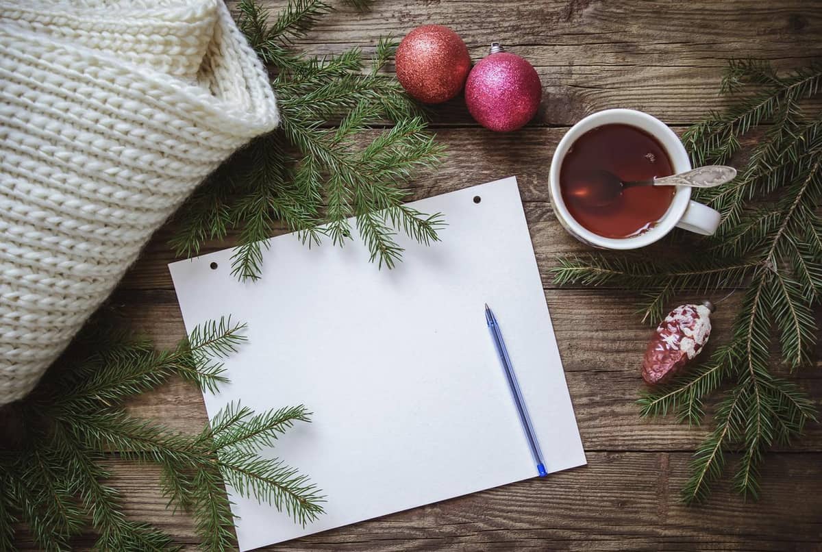 A piece of paper with a pen by it and a cup of tea with ornaments by it